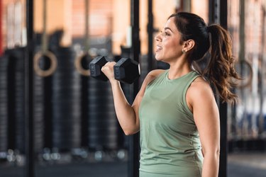 Close-up of person working out at gym with dumbbells to demonstrate an advanced 20-minute full-body workout.