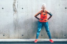 Woman standing against a concrete wall wearing colorful activewear