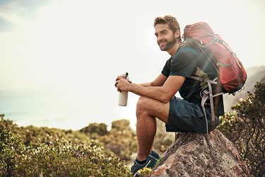 Fit guy wearing a backpack and hiking in the wilderness