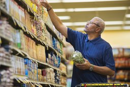 man shopping in grocery store reading ingredient list