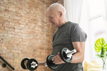 older adult performing biceps curls in living room as part of an at-home dumbbell workout for people over 50