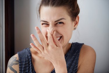A woman holding her nose because her farts smell really bad