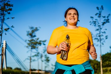 young woman in yellow shirt doing a walk-jog workout outside
