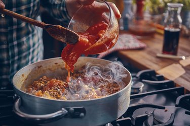 pouring tomato sauce into pan