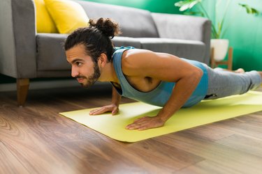 Person performing a Chaturanga Dandasana on yoga mat in living room