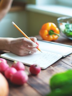 Woman writing meal plan in a journal