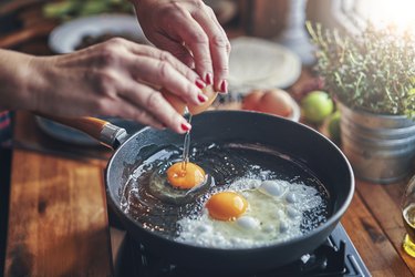 Frying an egg, one of the best foods to eat while pregnant, in a frying pan