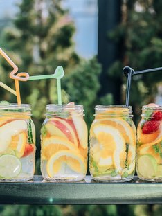 six fruity waters with sliced fruit and straws on table