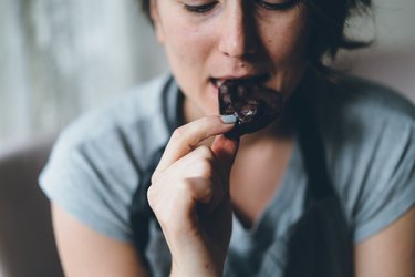 a close up photo of a person wearing a gray t-shirt eating dark chocolate and sweating while eating