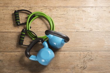 Flat Lay image of kettlebells and a resistance band on a wooden floor