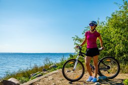 Woman cycling for exercise on trail near ocean