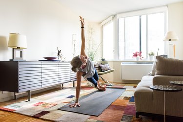 fit senior woman holding a side plank in her home on yoga mat