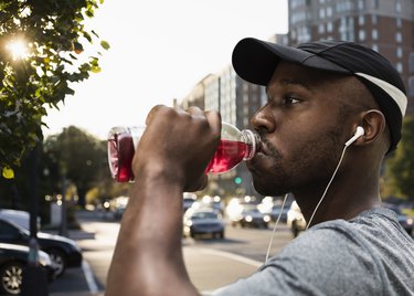 Close-up of runner drinking a sports drink outside for hydration.