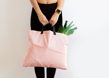 Fit woman holding a heavy pink bag full of groceries