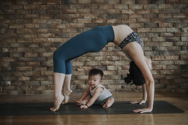 Woman doing an at-home yoga routine with her son on a yoga mat