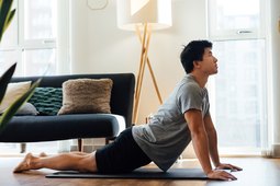 man practicing upward facing dog and stretching in his living room