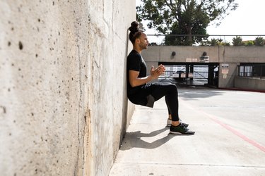 Man doing a wall sit exercise outside in the sunshine