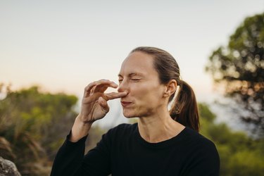 a person with a ponytail scratching their itchy nose outside