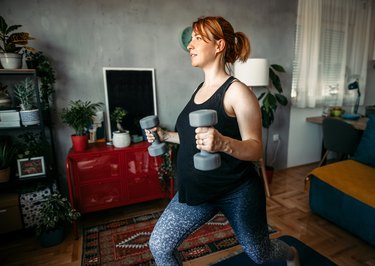Pregnant adult working out with dumbbells in living room