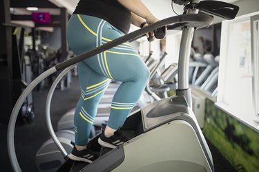 Person in a larger body wearing teal and yellow striped leggings working out on the stair stepper